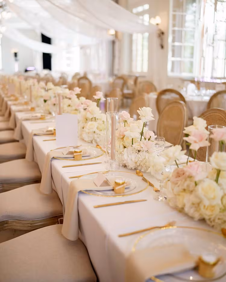 Aura Location mit heller Hochzeitstafel, Blumen und Goldbesteck