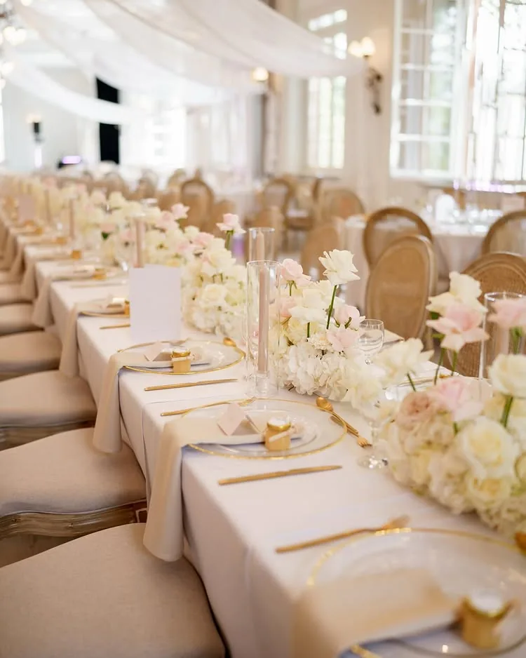 Aura Location mit heller Hochzeitstafel, Blumen und Goldbesteck