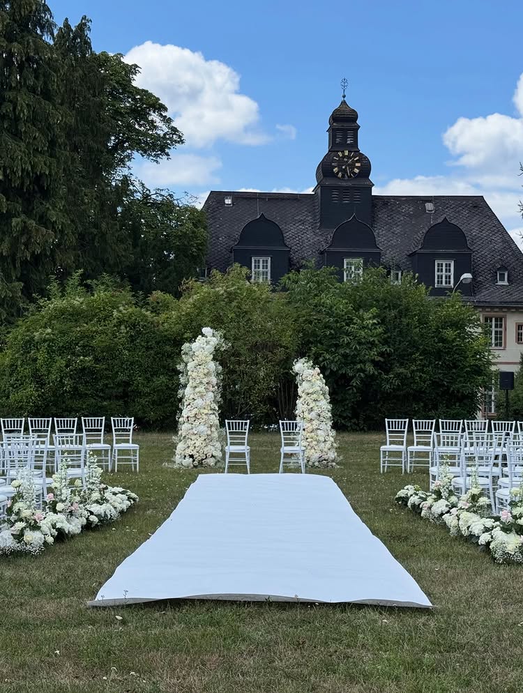 Freie Trauung im Außenbereich mit weißem Gang und Blumenbogen